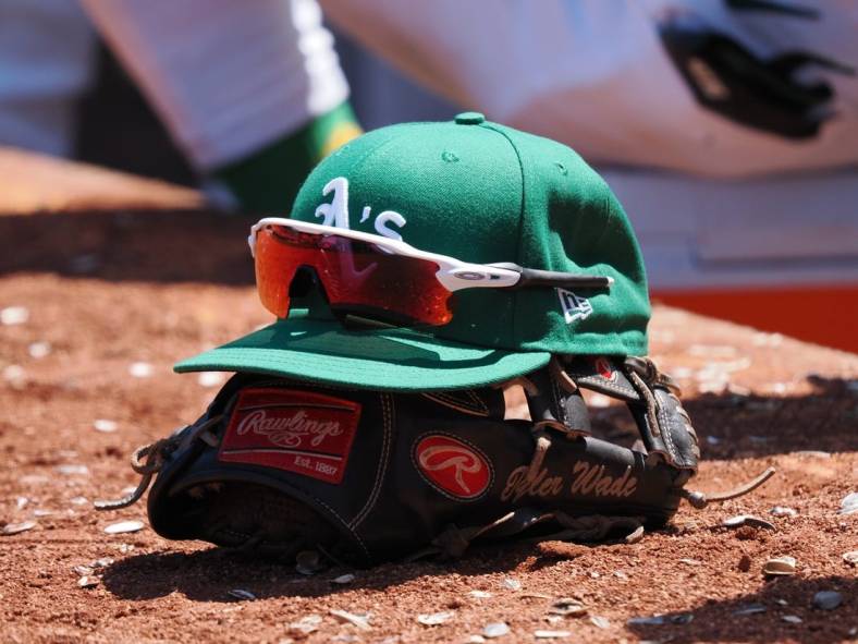 Jun 29, 2023; Oakland, California, USA; An Oakland Athletics hat on top of a glove during the eighth inning at Oakland-Alameda County Coliseum. Mandatory Credit: Kelley L Cox-USA TODAY Sports