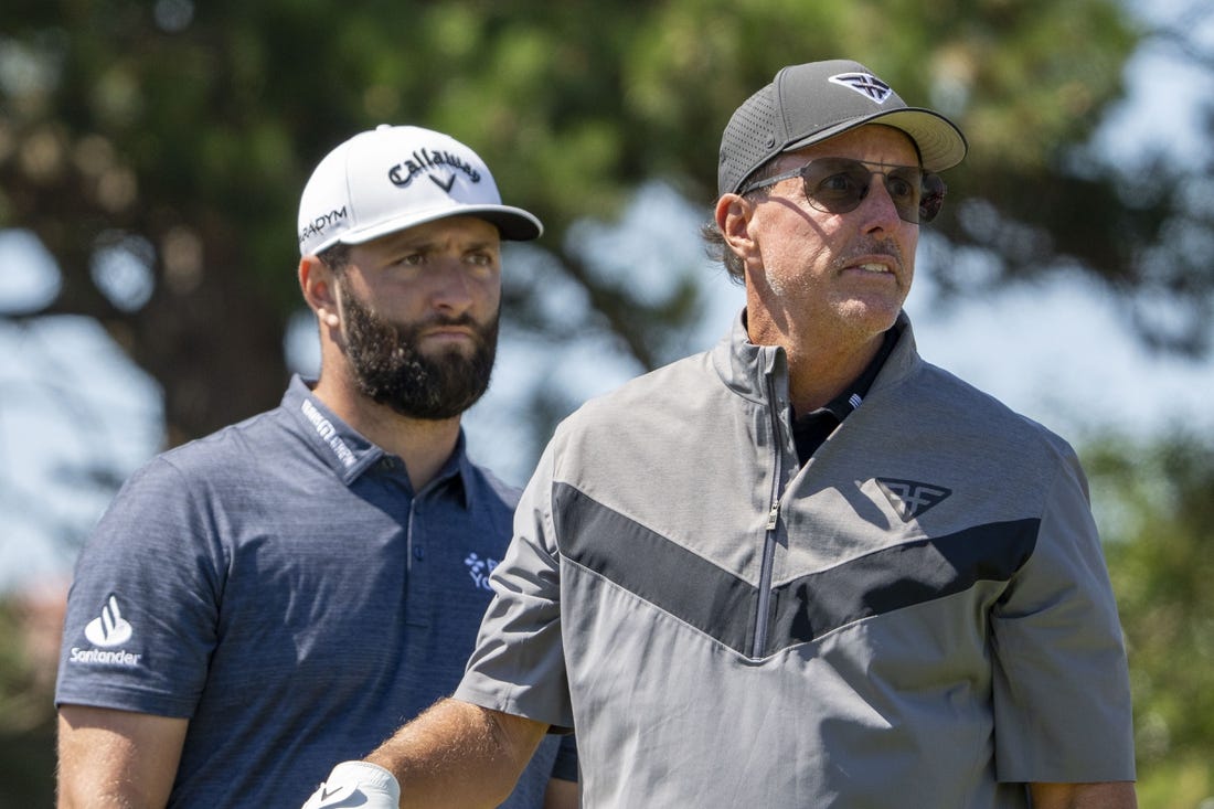 July 19, 2023; Hoylake, ENGLAND, GBR; Jon Rahm (left) watches the tee shot of Phil Mickelson (right) on the 18th hole during a practice round of The Open Championship golf tournament at Royal Liverpool. Mandatory Credit: Kyle Terada-USA TODAY Sports