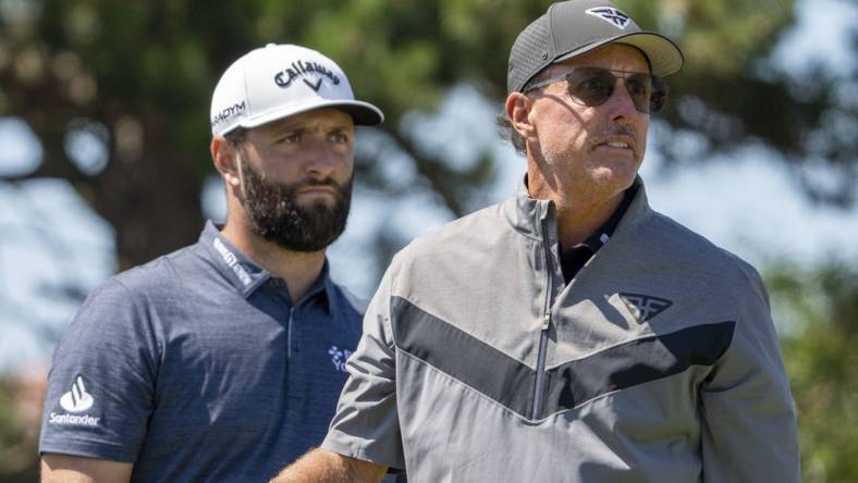 July 19, 2023; Hoylake, ENGLAND, GBR; Jon Rahm (left) watches the tee shot of Phil Mickelson (right) on the 18th hole during a practice round of The Open Championship golf tournament at Royal Liverpool. Mandatory Credit: Kyle Terada-USA TODAY Sports