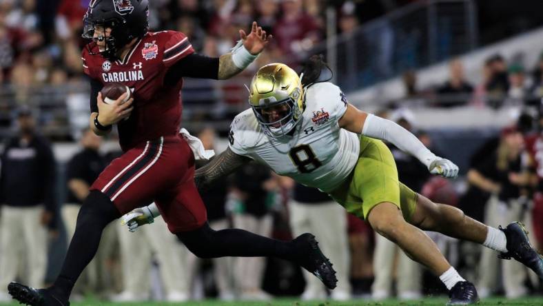 Notre Dame Fighting Irish linebacker Marist Liufau (8) tries to sack the South Carolina Quarterback Spencer Rattler (7). The University of Notre Dame Fighting Irish took on the University of South Carolina Gamecocks in the TaxSlayer Gator Bowl game in Jacksonville, Florida's TIAA Bank Field Friday, December 30, 2022. The first half ended with South Carolina holding a 24 to 17 lead.