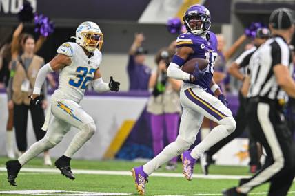 Sep 24, 2023; Minneapolis, Minnesota, USA; Minnesota Vikings wide receiver Justin Jefferson (18) scores on a touchdown pass as Los Angeles Chargers safety Alohi Gilman (32) chases from behind during the fourth quarter at U.S. Bank Stadium. Mandatory Credit: Jeffrey Becker-USA TODAY Sports