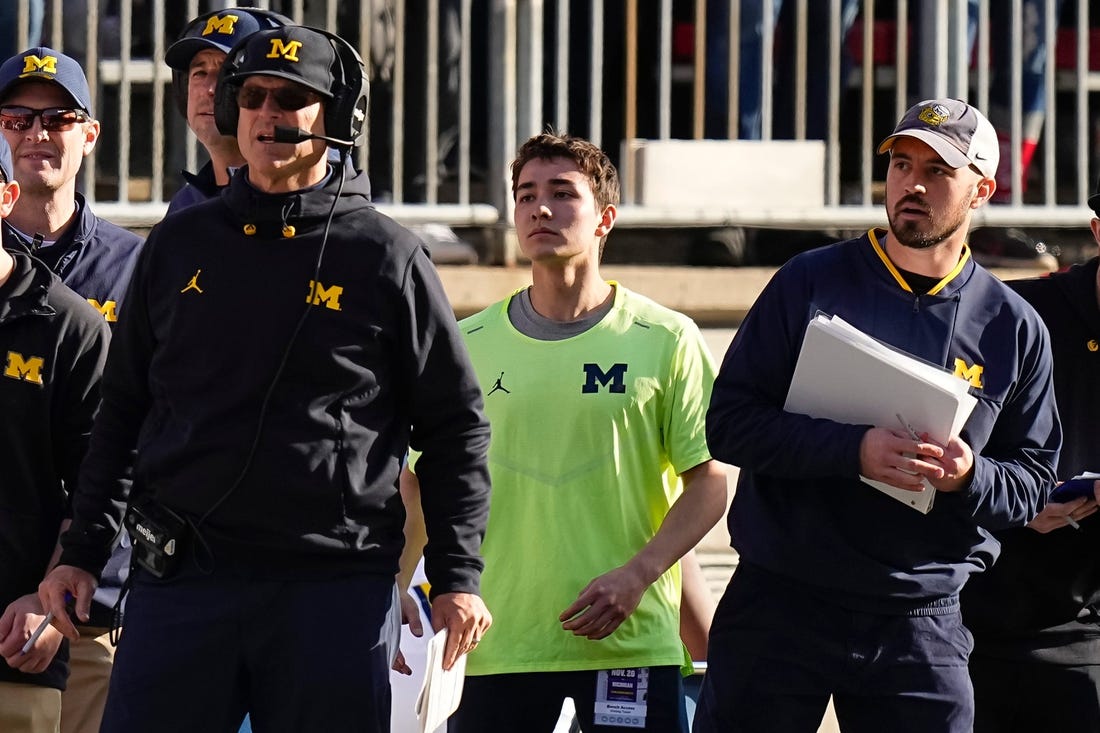 Nov 26, 2022; Columbus, Ohio, USA; Michigan Wolverines head coach Jim Harbaugh watches from the sideline beside off-field analyst Connor Stalions, right, during the NCAA football game against the Ohio State Buckeyes at Ohio Stadium.