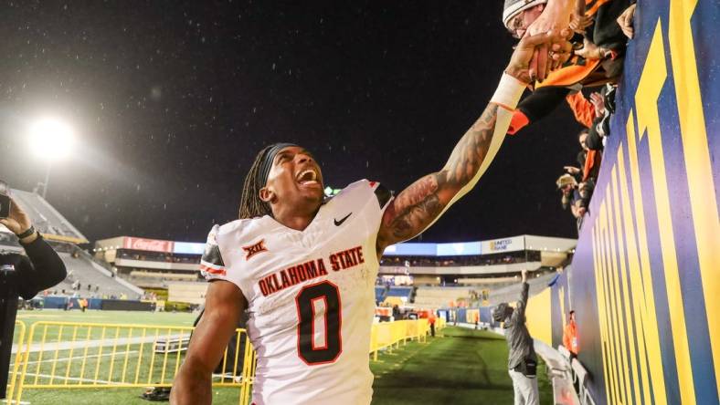 Oct 21, 2023; Morgantown, West Virginia, USA; Oklahoma State Cowboys running back Ollie Gordon II (0) celebrates with fans after defeating the West Virginia Mountaineers at Mountaineer Field at Milan Puskar Stadium. Mandatory Credit: Ben Queen-USA TODAY Sports