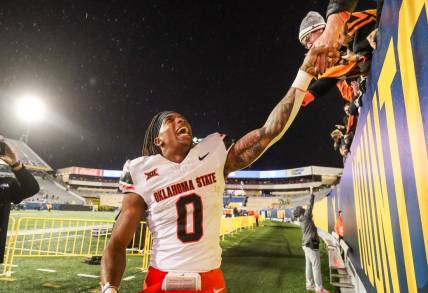 Oct 21, 2023; Morgantown, West Virginia, USA; Oklahoma State Cowboys running back Ollie Gordon II (0) celebrates with fans after defeating the West Virginia Mountaineers at Mountaineer Field at Milan Puskar Stadium. Mandatory Credit: Ben Queen-USA TODAY Sports
