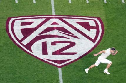 Oct 21, 2023; Stanford, California, USA; A view of the Pac-12 logo on the field as Stanford Cardinal wide receiver David Kasemervisz (80) warms up before the game against the UCLA Bruins at Stanford Stadium. Mandatory Credit: Darren Yamashita-USA TODAY Sports