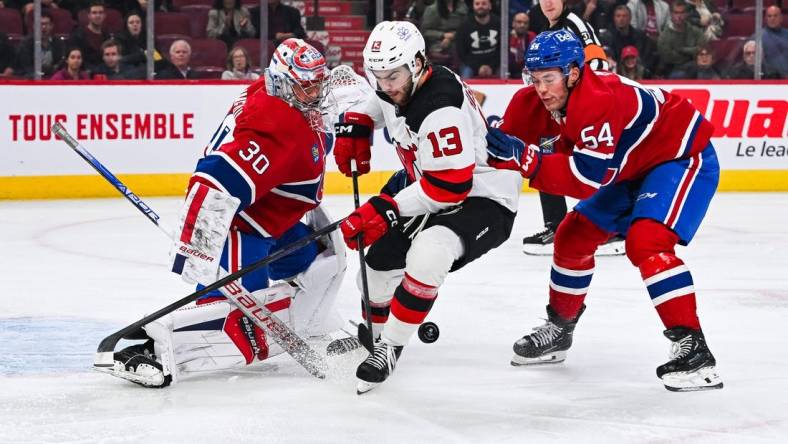 Oct 24, 2023; Montreal, Quebec, CAN; Montreal Canadiens goalie Cayden Primeau (30) makes a save against New Jersey Devils center Nico Hischier (13) with Montreal Canadiens defenseman Jordan Harris (54) help during the first period at Bell Centre. Mandatory Credit: David Kirouac-USA TODAY Sports