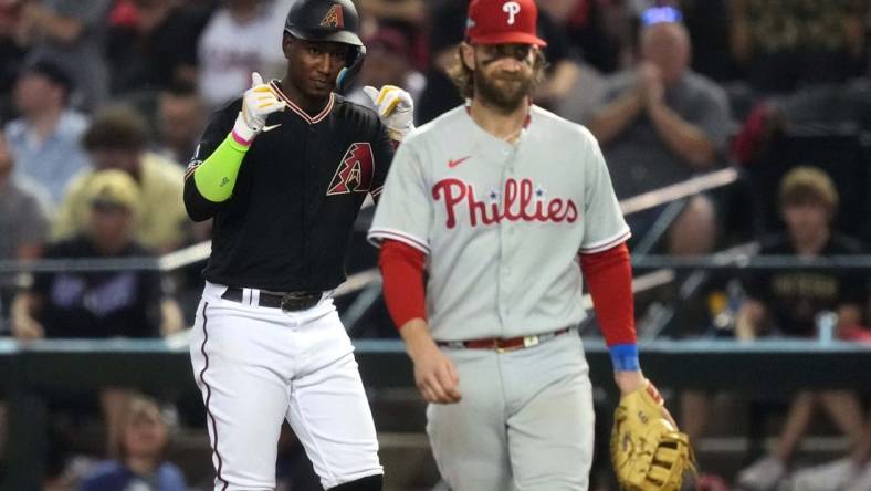 Arizona Diamondbacks shortstop Geraldo Perdomo (left) reacts after hitting a single during the seventh inning as Philadelphia Phillies first baseman Bryce Harper (right) looks on in game four of the NLCS of the 2023 MLB playoffs at Chase Field in Phoenix on Oct. 20, 2023.