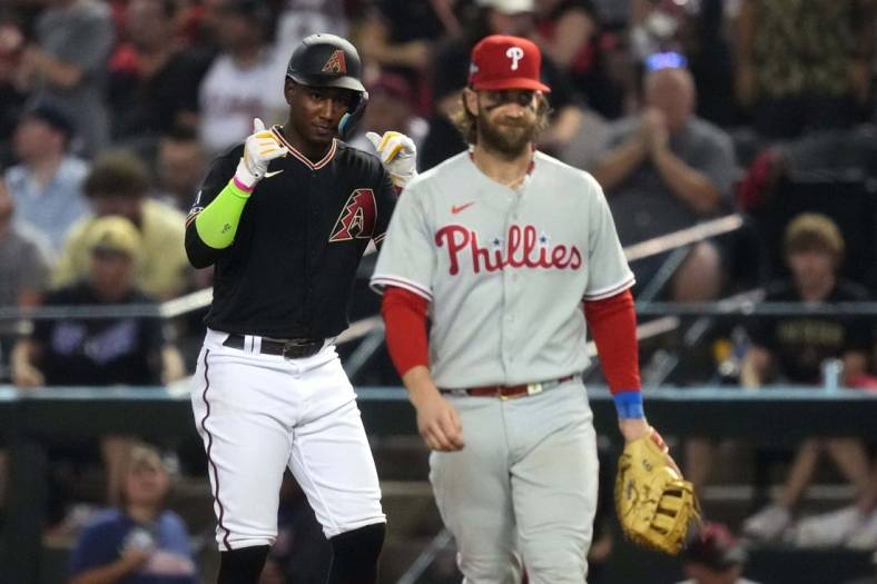 Arizona Diamondbacks shortstop Geraldo Perdomo (left) reacts after hitting a single during the seventh inning as Philadelphia Phillies first baseman Bryce Harper (right) looks on in game four of the NLCS of the 2023 MLB playoffs at Chase Field in Phoenix on Oct. 20, 2023.