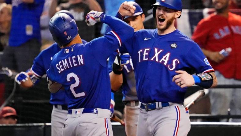 Texas Rangers second baseman Marcus Semien (2) celebrates with shortstop Corey Seager (5) after hitting a two run home run during the ninth inning against the Arizona Diamondbacks during game five of the 2023 World Series at Chase Field.