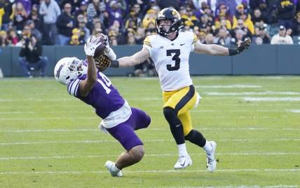 Nov 4, 2023; Chicago, Illinois, USA; Northwestern Wildcats wide receiver Cam Johnson (14) tries to catch a pass as Iowa Hawkeyes defensive back Cooper DeJean (3) defends during the first half at Wrigley Field. Mandatory Credit: David Banks-USA TODAY Sports