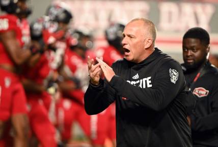 Nov 4, 2023; Raleigh, North Carolina, USA;  North Carolina State Wolfpack head coach Dave Doeren encourages his team as they warm up prior to a game against the Miami Hurricanes at Carter-Finley Stadium. Mandatory Credit: Rob Kinnan-USA TODAY Sports