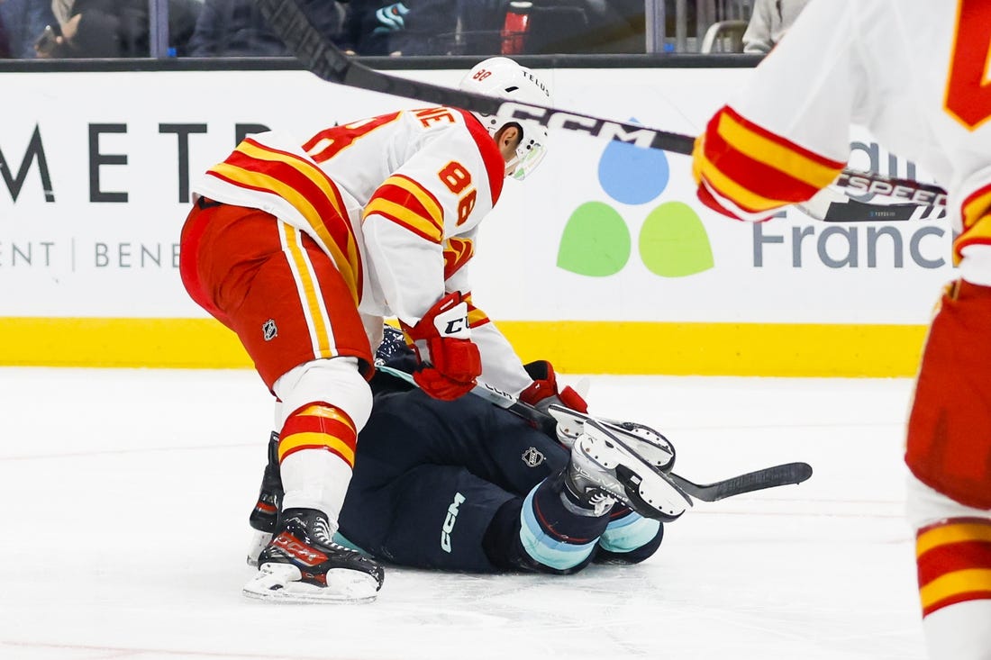 Nov 4, 2023; Seattle, Washington, USA; Calgary Flames left wing Andrew Mangiapane (88) cross-checks Seattle Kraken left wing Jared McCann (19) during the first period at Climate Pledge Arena. Mangiapane was given a major penalty for the play with intent to injure and ejected from the game. Mandatory Credit: Joe Nicholson-USA TODAY Sports