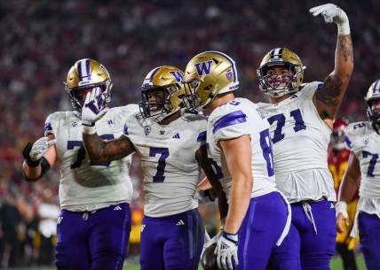 Nov 4, 2023; Los Angeles, California, USA; Washington Huskies running back Dillon Johnson (7), Washington Huskies offensive lineman Nate Kalepo (71) and other teammates celebrate against the USC Trojans during the second quarter at United Airlines Field at Los Angeles Memorial Coliseum. Mandatory Credit: Jonathan Hui-USA TODAY Sports