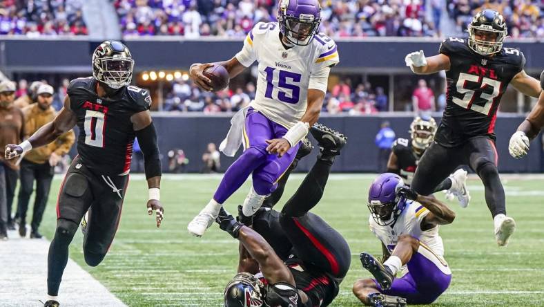 Nov 5, 2023; Atlanta, Georgia, USA; Minnesota Vikings quarterback Joshua Dobbs (15) jumps over Atlanta Falcons defensive tackle Kentavius Street (75) during the second half at Mercedes-Benz Stadium. Mandatory Credit: Dale Zanine-USA TODAY Sports