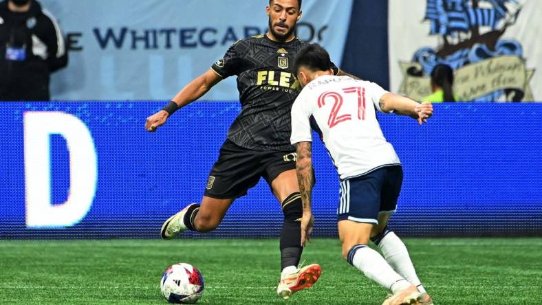 Nov 5, 2023; Vancouver, British Columbia, CAN; Los Angeles FC forward Denis Bouanga (99) kicks the ball against Vancouver Whitecaps midfielder Ryan Raposo (27) during the second half of game two in a round one match of the 2023 MLS Cup Playoffs at BC Place. Mandatory Credit: Simon Fearn-USA TODAY Sports