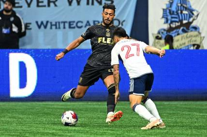 Nov 5, 2023; Vancouver, British Columbia, CAN; Los Angeles FC forward Denis Bouanga (99) kicks the ball against Vancouver Whitecaps midfielder Ryan Raposo (27) during the second half of game two in a round one match of the 2023 MLS Cup Playoffs at BC Place. Mandatory Credit: Simon Fearn-USA TODAY Sports