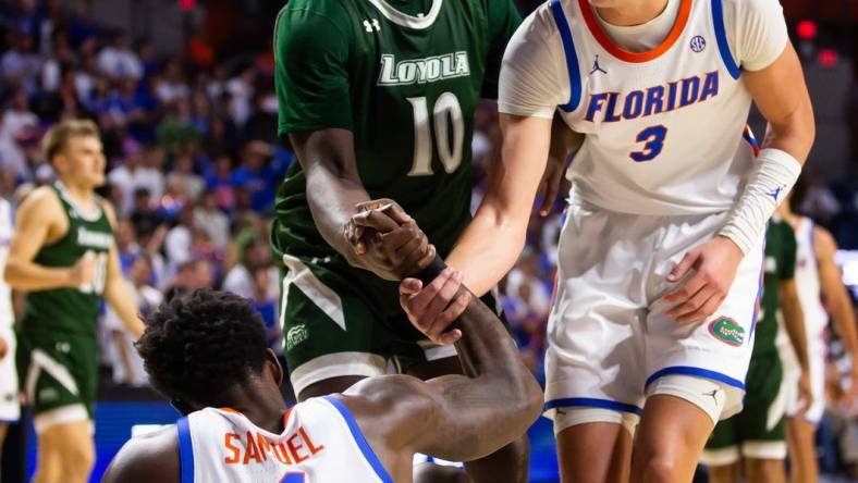 Florida Gators center Micah Handlogten (3) helps teammate Florida Gators forward Tyrese Samuel (4) up off the court. The Florida men   s basketball team hosted the Loyola Greyhounds at Exactech Arena at the Stephen C. O   Connell Center in Gainesville, FL on Monday, November 6, 2023 in the season opener. Gators lead 42-30 at the half. [Doug Engle/Ocala Star Banner]