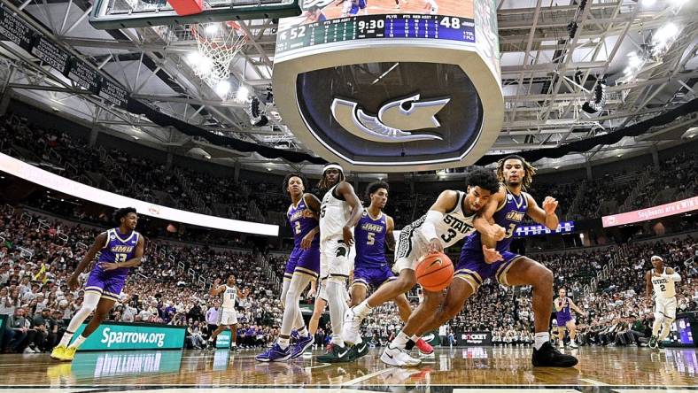 Nov 6, 2023; East Lansing, Michigan, USA; Michigan State Spartans guard Jaden Akins (3) battles with James Madison Dukes forward T.J. Bickerstaff (3) for a loose ball at Jack Breslin Student Events Center. Mandatory Credit: Dale Young-USA TODAY Sports