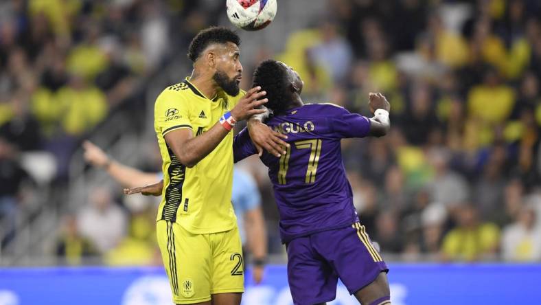 Nov 7, 2023; Nashville, Tennessee, USA; Nashville SC midfielder Anibal Godoy (20) heads the ball against Orlando City forward Ivan Angulo (77) in the second half at Geodis Park. Mandatory Credit: Steve Roberts-USA TODAY Sports