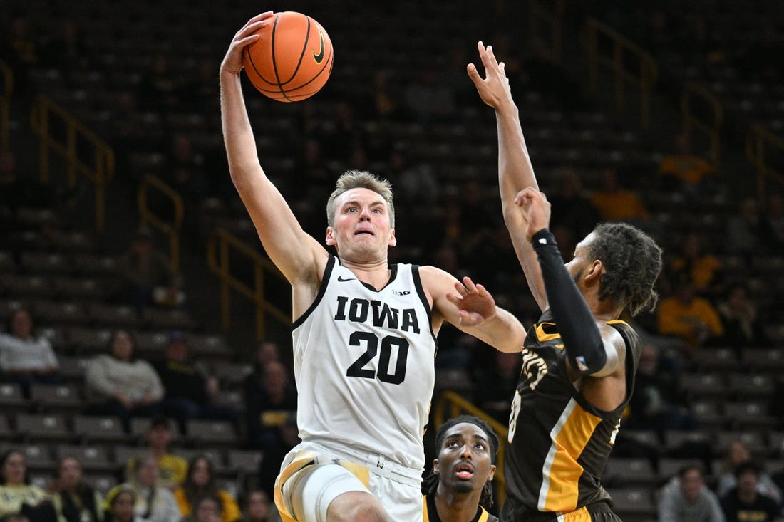 Oct 30, 2023; Iowa City, IA, USA; Iowa Hawkeyes forward Payton Sandfort (20) goes to the basket as Quincy University Hawks forward Jamil Wilson (23) and forward John Kelly III (4) defend during the first half at Carver Hawkeye Arena. Mandatory Credit: Jeffrey Becker-USA TODAY Sports