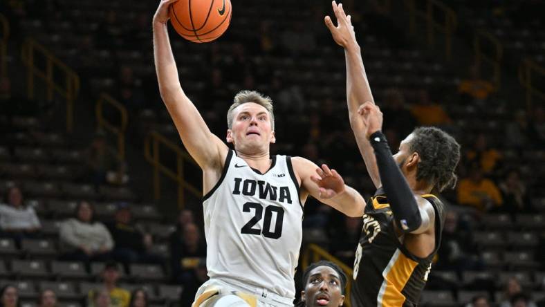 Oct 30, 2023; Iowa City, IA, USA; Iowa Hawkeyes forward Payton Sandfort (20) goes to the basket as Quincy University Hawks forward Jamil Wilson (23) and forward John Kelly III (4) defend during the first half at Carver Hawkeye Arena. Mandatory Credit: Jeffrey Becker-USA TODAY Sports