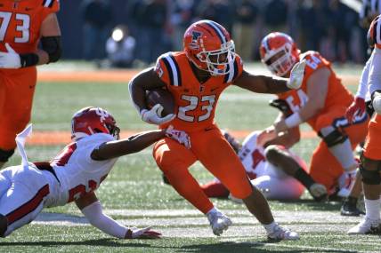 Nov 11, 2023; Champaign, Illinois, USA;  Illinois Fighting Illini running back Reggie Love III (23) eludes the tackle of Indiana Hoosiers defensive back Louis Moore (20) during the first half at Memorial Stadium. Mandatory Credit: Ron Johnson-USA TODAY Sports