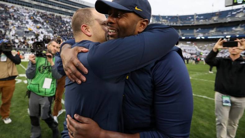 Nov 11, 2023; University Park, Pennsylvania, USA; Michigan Wolverines offensive line coach Sherrone Moore hugs an assistant coach following a game against the Penn State Nittany Lions at Beaver Stadium. Michigan won 24-15. Mandatory Credit: Matthew O'Haren-USA TODAY Sports