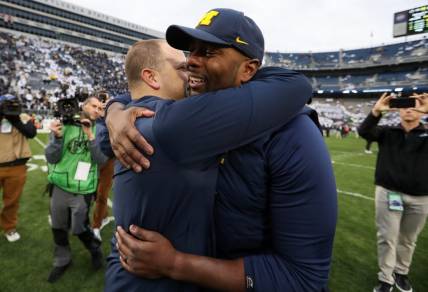 Nov 11, 2023; University Park, Pennsylvania, USA; Michigan Wolverines offensive line coach Sherrone Moore hugs an assistant coach following a game against the Penn State Nittany Lions at Beaver Stadium. Michigan won 24-15. Mandatory Credit: Matthew O'Haren-USA TODAY Sports