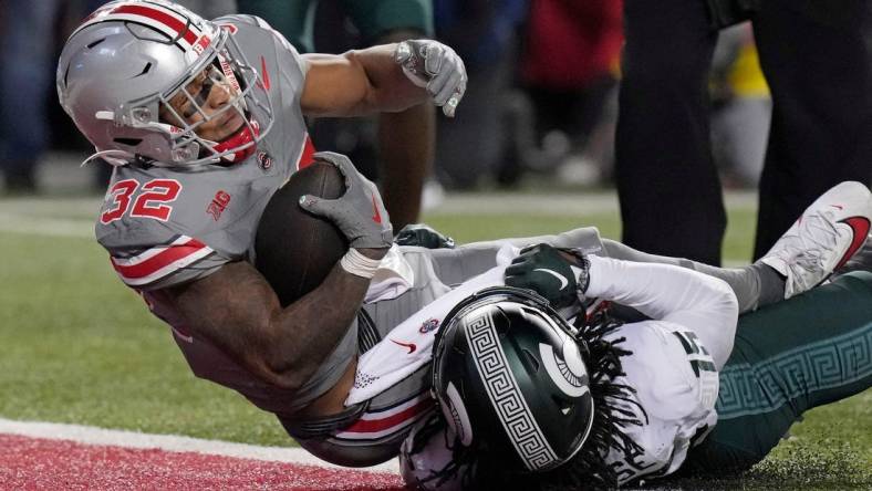 Nov. 11, 2023; Columbus, Oh., USA; 
Ohio State Buckeyes running back TreVeyon Henderson (32) dives into the endzone (32) while he is tackled by Michigan State Spartans defensive back Angelo Grose (15) to score a touchdown during the first half of Saturday's NCAA Division I football game at Ohio Stadium.