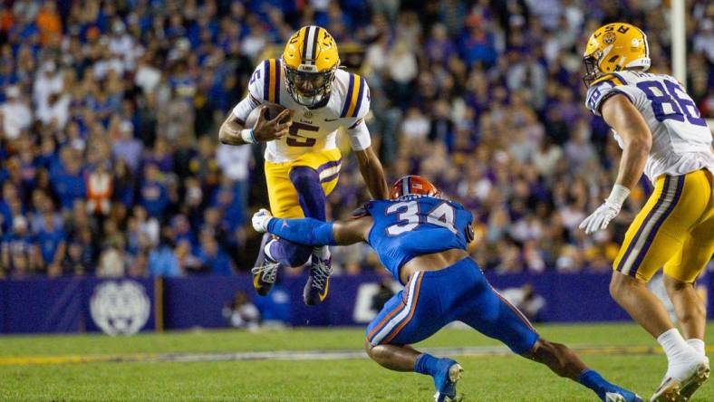 Nov 11, 2023; Baton Rouge, Louisiana, USA;  LSU Tigers quarterback Jayden Daniels (5) attempts to leap over the arms of Florida Gators linebacker Mannie Nunnery (34) during the first half at Tiger Stadium. Mandatory Credit: Stephen Lew-USA TODAY Sports