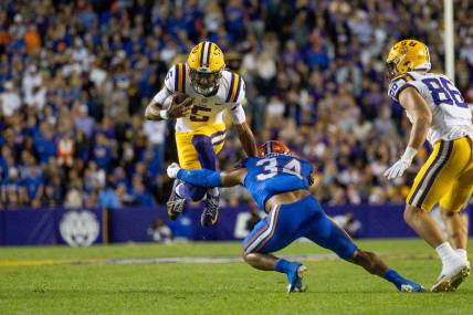 Nov 11, 2023; Baton Rouge, Louisiana, USA;  LSU Tigers quarterback Jayden Daniels (5) attempts to leap over the arms of Florida Gators linebacker Mannie Nunnery (34) during the first half at Tiger Stadium. Mandatory Credit: Stephen Lew-USA TODAY Sports