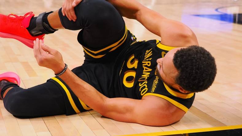 Nov 12, 2023; San Francisco, California, USA; Golden State Warriors guard Stephen Curry (30) holds his leg as he goes down on the floor during the fourth quarter against the Minnesota Timberwolves at Chase Center. Mandatory Credit: Kelley L Cox-USA TODAY Sports