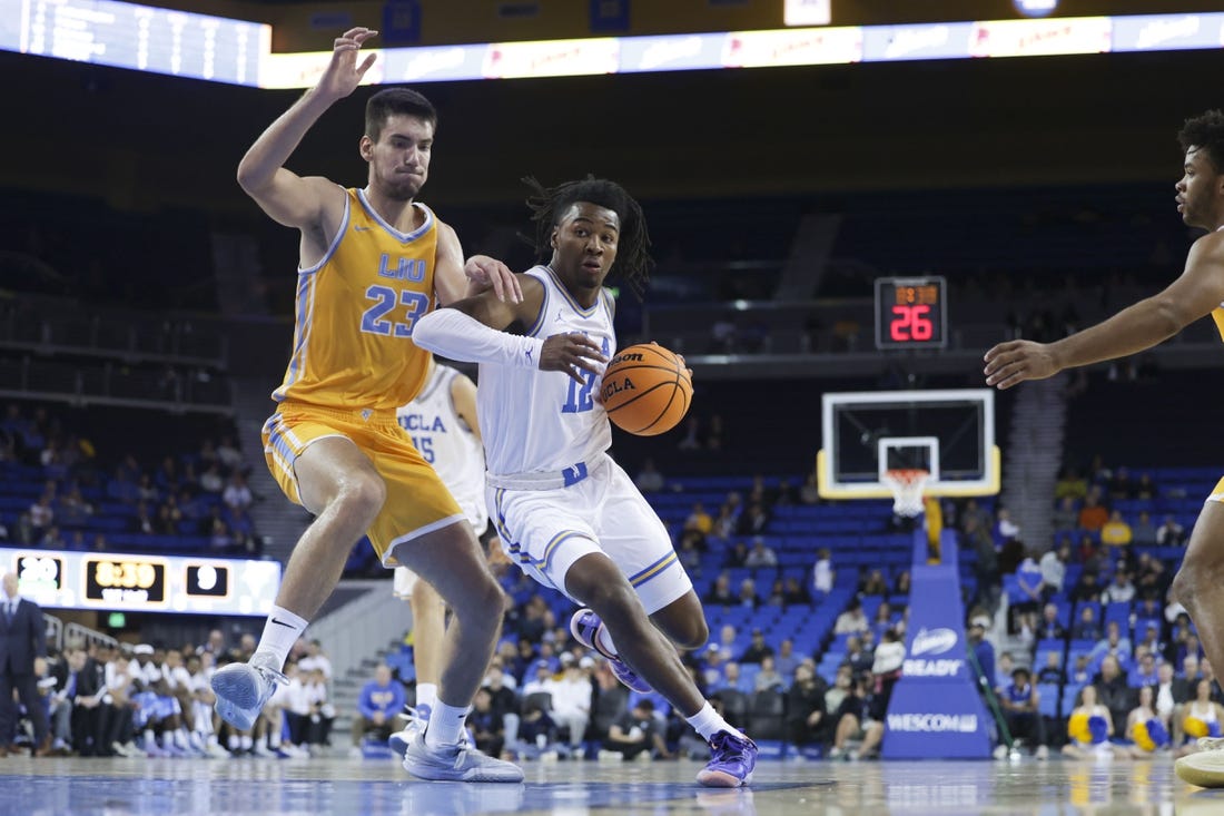 Nov 15, 2023; Los Angeles, California, USA; UCLA guard Sebastian Mack (12) drives the ball against Long Island University forward Nikola Djapa (23) during the first half at Pauley Pavilion presented by Wescom. Mandatory Credit: Yannick Peterhans-USA TODAY Sports