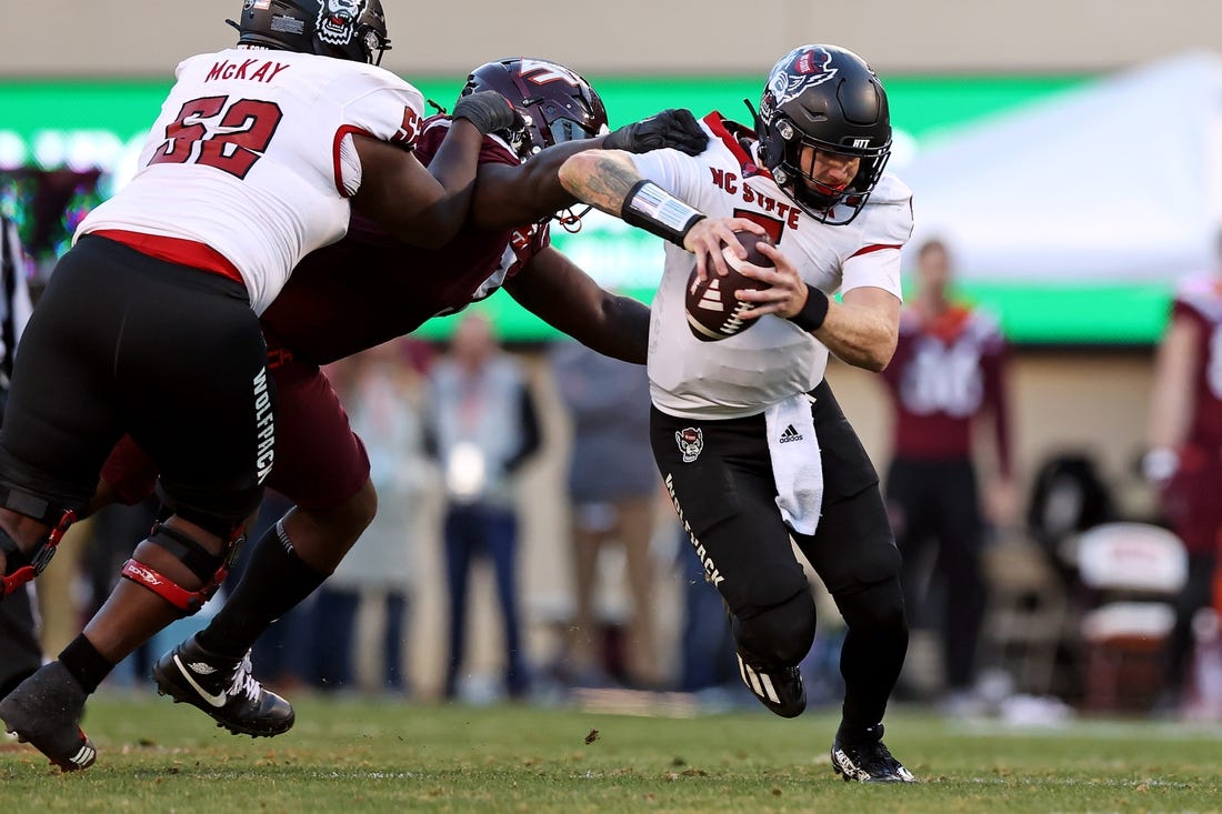 Nov 18, 2023; Blacksburg, Virginia, USA; North Carolina State Wolfpack quarterback Brennan Armstrong (5) runs from Virginia Tech Hokies defensive lineman Norell Pollard (3) during the second quarter at Lane Stadium. Mandatory Credit: Peter Casey-USA TODAY Sports