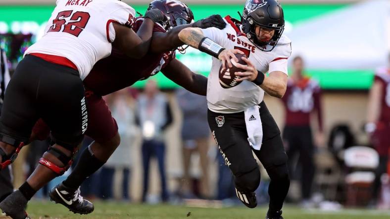 Nov 18, 2023; Blacksburg, Virginia, USA; North Carolina State Wolfpack quarterback Brennan Armstrong (5) runs from Virginia Tech Hokies defensive lineman Norell Pollard (3) during the second quarter at Lane Stadium. Mandatory Credit: Peter Casey-USA TODAY Sports