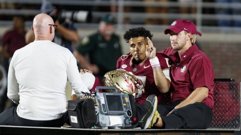 Nov 18, 2023; Tallahassee, Florida, USA; Florida State Seminoles quarterback Jordan Travis (13) waves to fans while being carted off after an injury against the North Alabama Lions during the first quarter at Doak S. Campbell Stadium. Mandatory Credit: Morgan Tencza-USA TODAY Sports