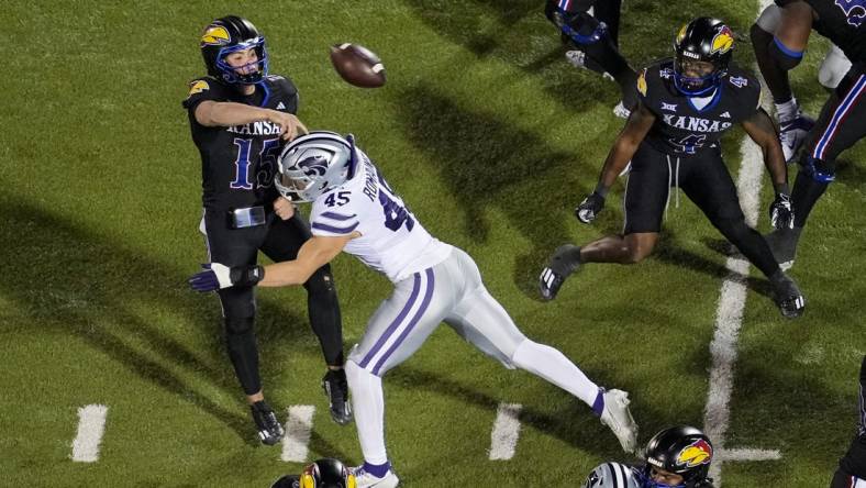 Nov 18, 2023; Lawrence, Kansas, USA; Kansas Jayhawks quarterback Cole Ballard (15) throws a touchdown pass as he is hit by Kansas State Wildcats linebacker Austin Romaine (45) during the first half at David Booth Kansas Memorial Stadium. Mandatory Credit: Jay Biggerstaff-USA TODAY Sports