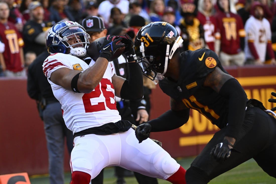 Nov 19, 2023; Landover, Maryland, USA; New York Giants running back Saquon Barkley (26) catches a touchdown  past Washington Commanders safety Kamren Curl (31) during the first half at FedExField. Mandatory Credit: Brad Mills-USA TODAY Sports