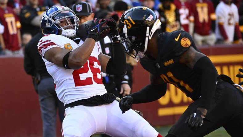 Nov 19, 2023; Landover, Maryland, USA; New York Giants running back Saquon Barkley (26) catches a touchdown  past Washington Commanders safety Kamren Curl (31) during the first half at FedExField. Mandatory Credit: Brad Mills-USA TODAY Sports