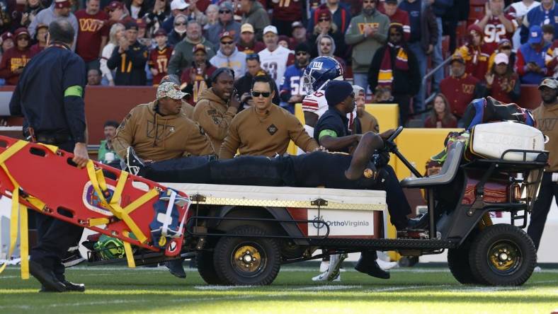 Nov 19, 2023; Landover, Maryland, USA; Washington Commanders defensive end Efe Obada (97) is carted off the field after being injured against the New York Giants during the first quarter at FedExField. Mandatory Credit: Geoff Burke-USA TODAY Sports