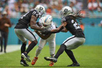Nov 19, 2023; Miami Gardens, Florida, USA; Miami Dolphins wide receiver Jaylen Waddle (17) runs with the football as Las Vegas Raiders cornerback Marcus Peters (24) and safety Tre'von Moehrig (25) attempt to him during the second quarter at Hard Rock Stadium. Mandatory Credit: Sam Navarro-USA TODAY Sports