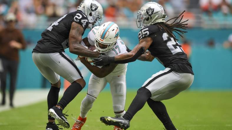 Nov 19, 2023; Miami Gardens, Florida, USA; Miami Dolphins wide receiver Jaylen Waddle (17) runs with the football as Las Vegas Raiders cornerback Marcus Peters (24) and safety Tre'von Moehrig (25) attempt to him during the second quarter at Hard Rock Stadium. Mandatory Credit: Sam Navarro-USA TODAY Sports