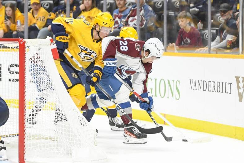Nov 20, 2023; Nashville, Tennessee, USA;  Nashville Predators center Juuso Parssinen (75) and Colorado Avalanche left wing Miles Wood (28) fight for the puck during the second period at Bridgestone Arena. Mandatory Credit: Steve Roberts-USA TODAY Sports