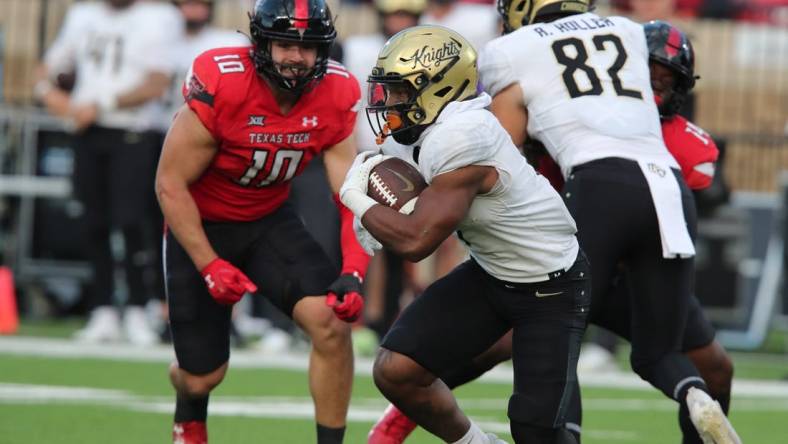 Nov 18, 2023; Lubbock, Texas, USA;  Central Florida Knights running back RJ Harvey (7) rushes against Texas Tech Red Raiders defensive end Jacob Rodriguez (10) in the first half at Jones AT&T Stadium and Cody Campbell Field. Mandatory Credit: Michael C. Johnson-USA TODAY Sports