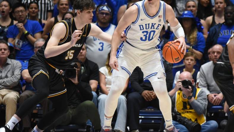 Nov 21, 2023; Durham, North Carolina, USA; Duke Blue Devils center Kyle Filipowski (30) controls the ball in front of La Salle Explorers forward Rokas Jucius (35) during the first half at Cameron Indoor Stadium. Mandatory Credit: Rob Kinnan-USA TODAY Sports