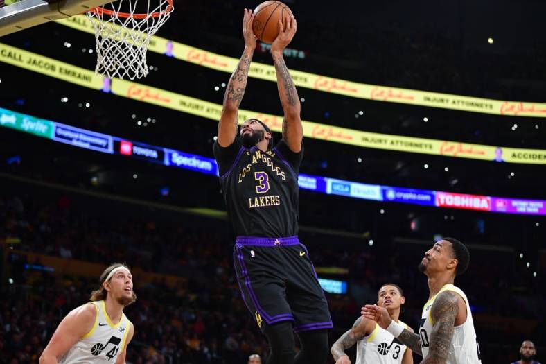 Nov 21, 2023; Los Angeles, California, USA; Los Angeles Lakers forward Anthony Davis (3) moves to the basket ahead of Utah Jazz forward John Collins (20) and forward Kelly Olynyk (41) during the first half at Crypto.com Arena. Mandatory Credit: Gary A. Vasquez-USA TODAY Sports