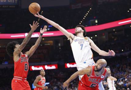 Nov 22, 2023; Oklahoma City, Oklahoma, USA; Oklahoma City Thunder forward Chet Holmgren (7) reaches for a loose ball over Chicago Bulls guard Coby White (0) and guard Jevon Carter (5) during the second quarter at Paycom Center. Mandatory Credit: Alonzo Adams-USA TODAY Sports
