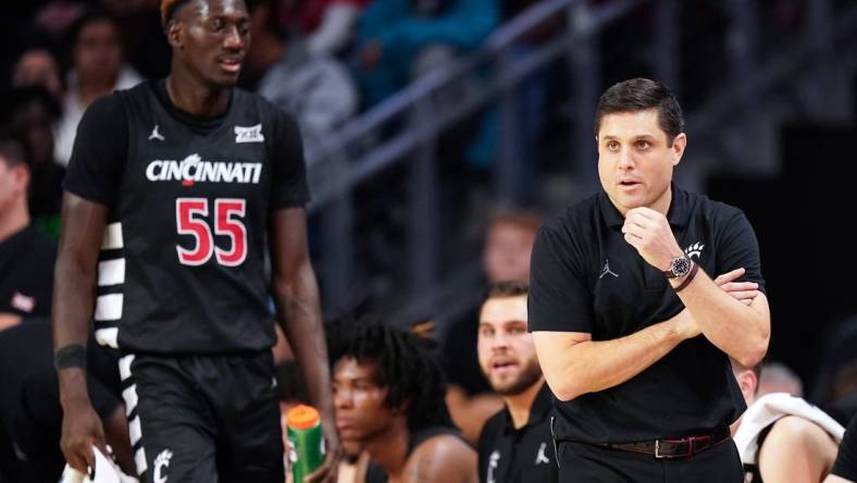 Cincinnati Bearcats head coach Wes Miller paces the sideline as Cincinnati Bearcats forward Aziz Bandaogo (55) finds a seat on the bench in the first half during an NCAA college basketball game between Georgia Tech Yellow Jackets and the Cincinnati Bearcats, Wednesday, Nov. 22, 2023, at Fifth Third Arena in Cincinnati.