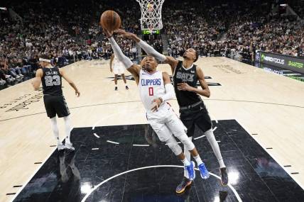 Nov 22, 2023; San Antonio, Texas, USA; Los Angeles Clippers guard Russell Westbrook (0) lays in a basket while defended by San Antonio Spurs forward Victor Wembanyama (1) during the second half at Frost Bank Center. Mandatory Credit: Scott Wachter-USA TODAY Sports
