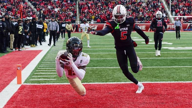 Nov 25, 2023; Salt Lake City, Utah, USA; Colorado Buffaloes athlete Travis Hunter (12) dives for a catch in the end zone in front of Utah Utes cornerback Zemaiah Vaughn (5) at Rice-Eccles Stadium. Mandatory Credit: Christopher Creveling-USA TODAY Sports